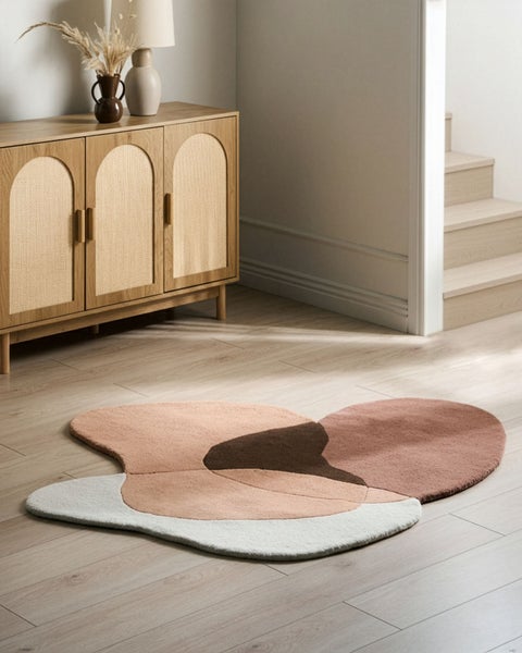 Moderner Wohnraum mit unregelmäßig geformtem Teppich in Erdtönen auf hellem Holzboden neben einem Holzsideboard mit Rattantüren.