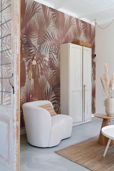 Wohnzimmer mit gemusterter Tapete, Sessel und Kleiderschrank