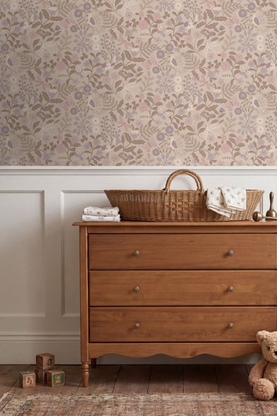 Vliestapete mit floralem Muster, Vögeln und Schmetterlingen über weißer Wandtäfelung und einer Holzkommode in einem hellen Kinderzimmer.
