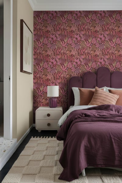 Schlafzimmer mit gemusterter Tapete, Bett, Nachttischlampe und Teppich