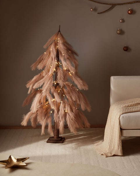 Dekorativer Federbaum mit Beleuchtung neben Sofa und Dekoration