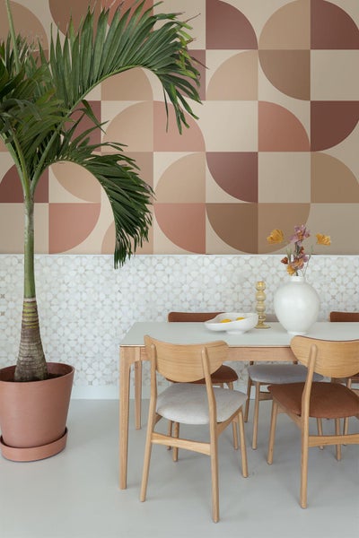 Esszimmer mit Esstisch, Stühlen, Zimmerpflanze und dekorativer Wandgestaltung