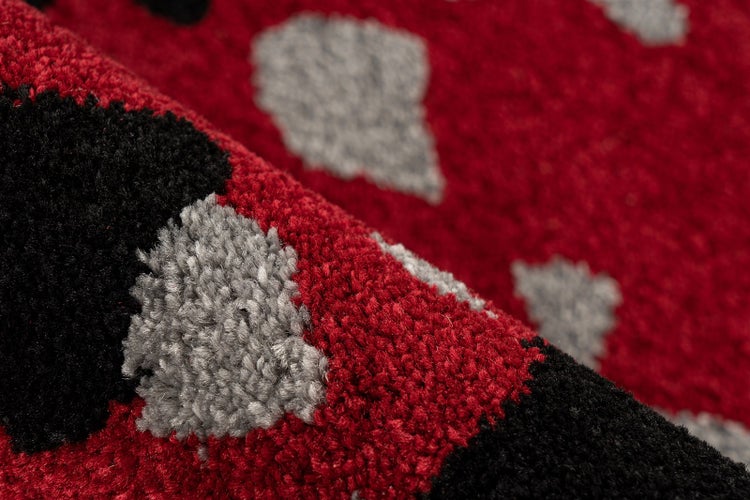 Nahaufnahme eines weichen Hochflor-Teppichs mit großem Punktmuster in Rot, Schwarz und Grau.