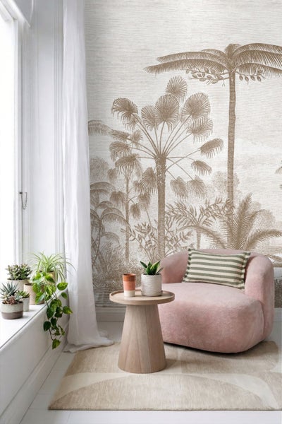 Fototapete mit skizzierten Palmen in Beige im hellen Wohnzimmer mit rosa Sessel und Holzbeistelltisch.