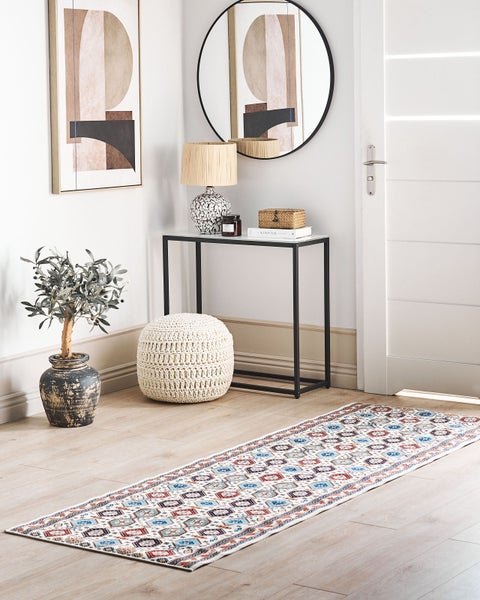 Heller Flur mit geometrischem Läufer, schwarzem Konsolentisch, weißem Strick-Pouf und künstlichem Olivenbaum in rustikalem Topf.