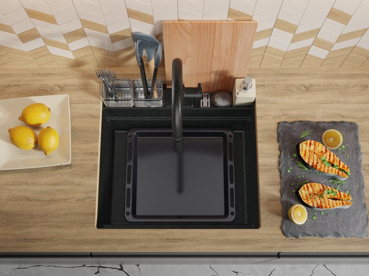 Spüle mit Armatur, Abtropfbecken, Geschirr, Schneidebrett, Spülmittel und zubereitetem Fisch auf einem Küchentisch.