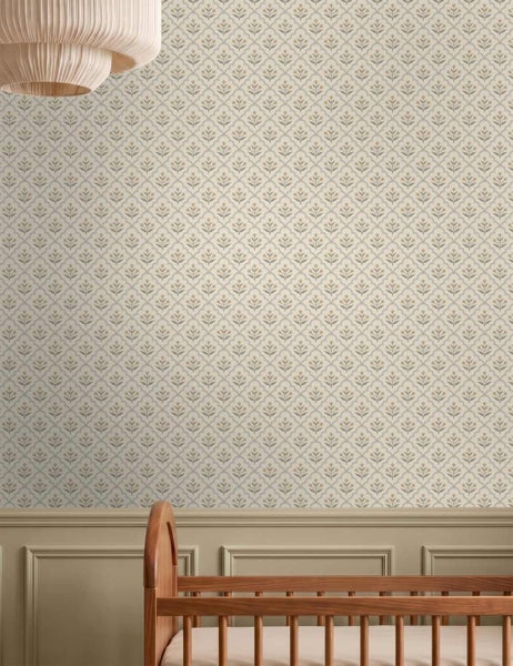 Vliestapete mit floralem Ornamentmuster in einem hellen Kinderzimmer über einer Wandvertäfelung und einem Kinderbett aus Holz.