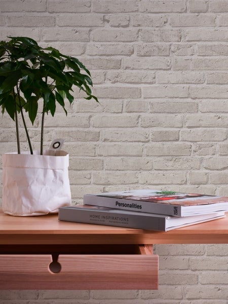Dekorative Wand mit Tapete in Ziegeloptik, Tisch mit Pflanze und Bild