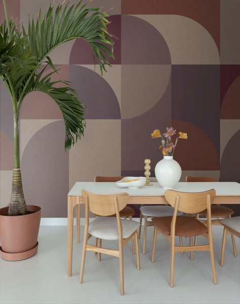 Esszimmer mit Esstisch, Stühlen, Zimmerpflanze und geometrischer Mustertapete