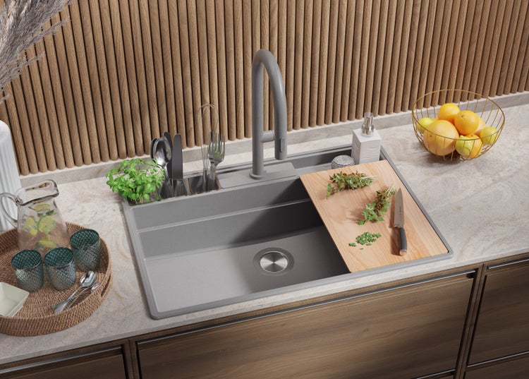 Küchenspüle mit Abtropffläche, Armatur, Schneidebrett und Küchenutensilien auf einer Küchentheke.