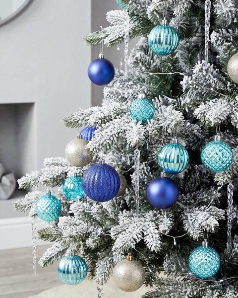 Weihnachtsbaum mit Kunstschnee dekoriert mit Christbaumkugeln und Eiszapfen Anhaengern in verschiedenen Formen und Strukturen