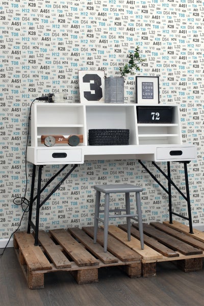 Schreibtisch mit Regalen, Schubladen und einem grauen Hocker auf Holzpaletten.