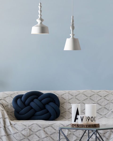 Szene mit zwei Pendelleuchten, einem Sofa mit Zierkissen und einem Tisch mit Dekoration