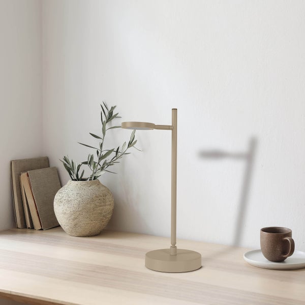 Szene mit einer Tischleuchte, einer Vase mit Zweigen, Büchern und einer Tasse auf einem Schreibtisch.