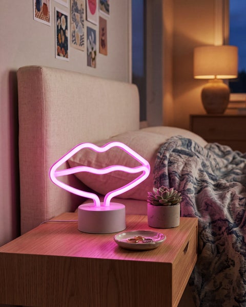 LED Neon Tischleuchte in Lippenform auf einem Nachttisch in einem gemütlichen Schlafzimmer