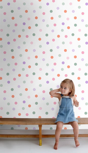 Kind sitzt vor einer Wand mit einem Punktmuster