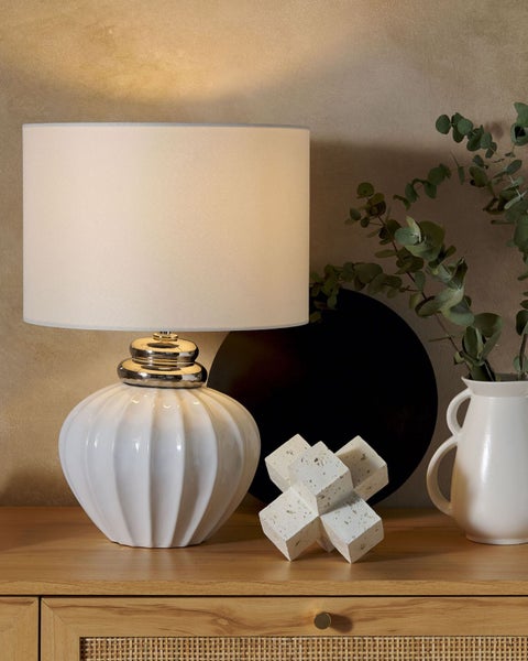 Dekorative Tischlampe mit weißem Lampenschirm auf einem Holztisch