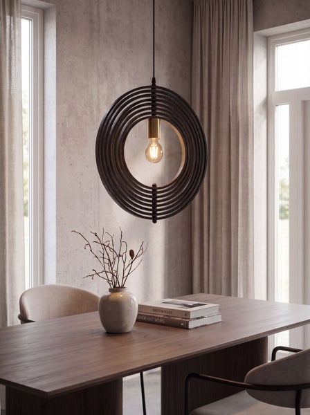 Moderne runde Pendelleuchte mit Metallringen über einem Esstisch aus Holz in einem hellen, stilvoll eingerichteten Essbereich.
