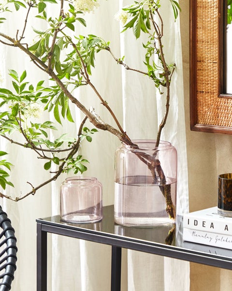 Dekorative Glasvasen auf einem Tisch mit Pflanzenzweigen