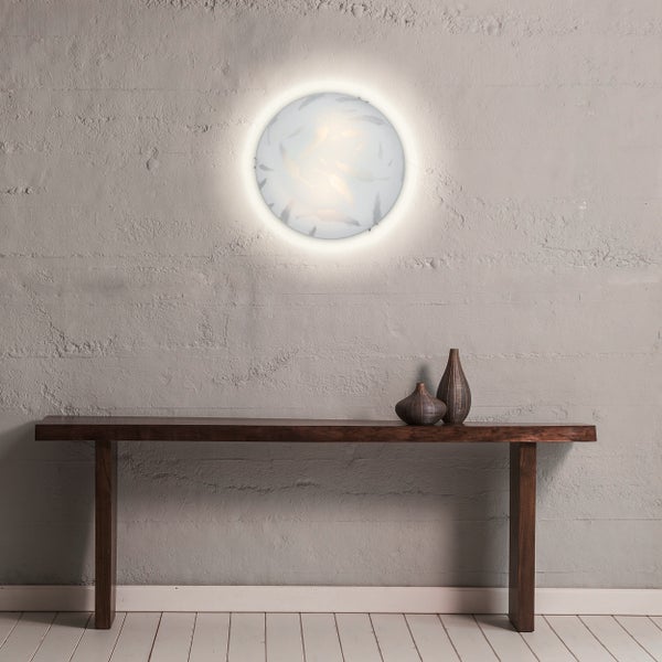 Wandleuchte mit Federdesign über einem dunklen Holztisch mit Vasen