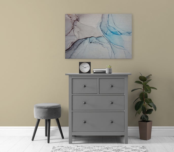 Eine moderne Kommode mit vier Schubladen, kombiniert mit einem kleinen Hocker, einem Wandbild und einer Zimmerpflanze in einem Wohnraum.