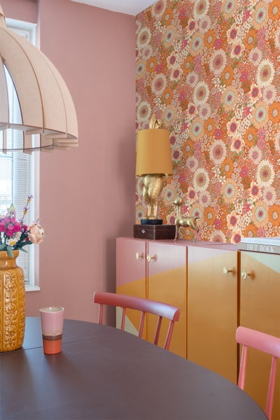 Esszimmer mit floraler Tapete, Schrank, Tisch und Stühlen.