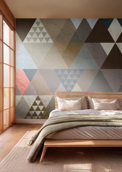 Schlafzimmer mit geometrischer Tapete in verschiedenen Farben und einem Holzbett.