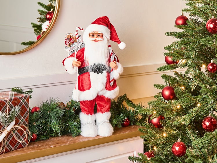 Weihnachtliche Dekoration mit Weihnachtsmannfigur, Weihnachtsbaum und Geschenk