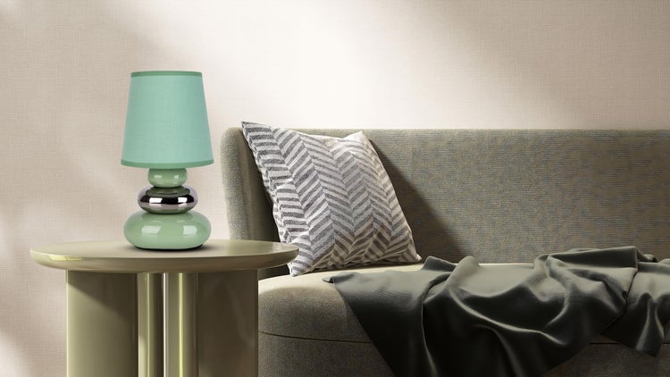 Dekorative grüne Lampe auf einem Beistelltisch neben einem Sofa mit Kissen und Decke.