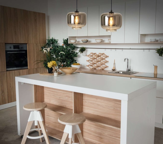 Küchenszene mit Kücheninsel, Barhockern und zwei Pendelleuchten