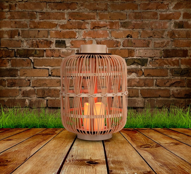 Dekorative Laterne mit LED-Kerzen vor einer Ziegelwand