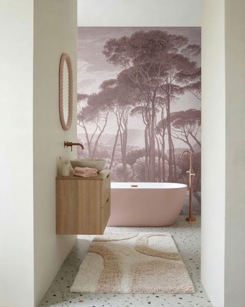 Modernes Badezimmer mit rosa freistehender Badewanne, Holz-Waschtischunterschrank, Steinwaschbecken und einer Fototapete mit Waldmotiv.