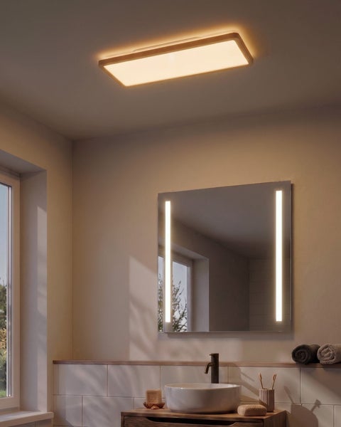 Badezimmer mit rechteckigem LED Spiegel und Deckenleuchte mit Holzrahmen über einem Waschbecken mit Armatur.