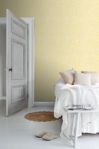 Schlafzimmer mit geometrischer Tapete, Bett und offener Tür