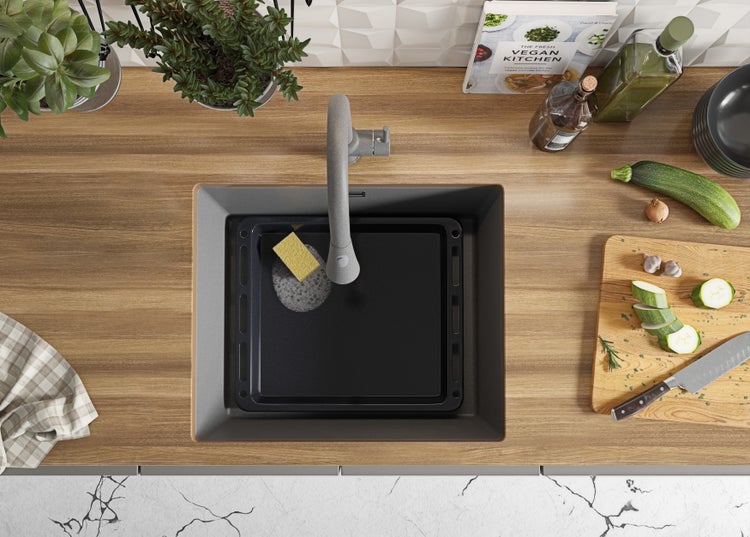 Spüle mit Armatur, Spülschüssel, Schwamm und Küchenutensilien auf einer Küchentheke