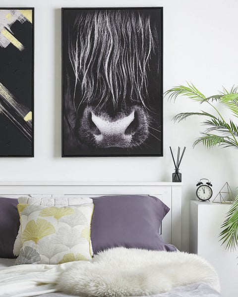 Schlafzimmer mit Bett, Kissen, Dekoration und zwei gerahmten Bildern an der Wand