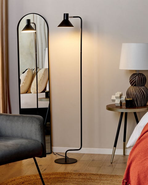 Helles Schlafzimmer mit Stehlampe, Spiegel und Sessel