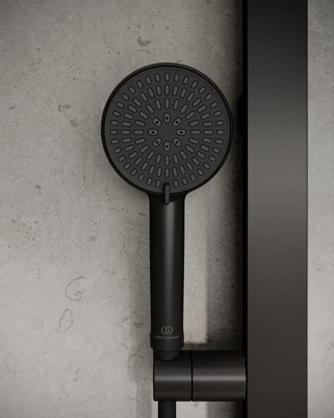 Matte schwarze runde Handbrause mit Ideal Standard Logo und zahlreichen Strahldüsen, an einer Duschstange befestigt.
