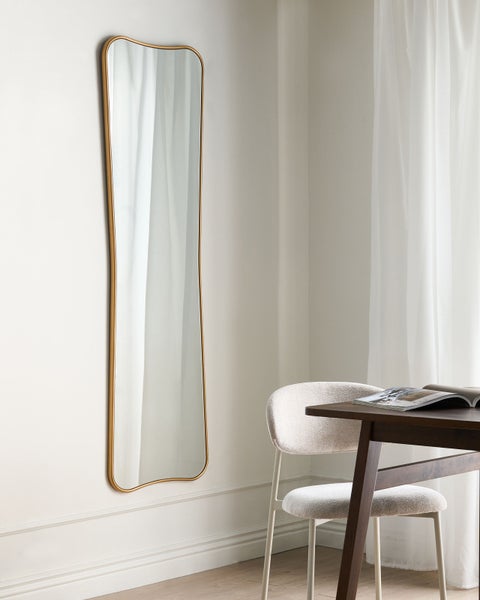 Zimmerszene mit hohem Spiegel mit Metallrahmen, Stuhl und Tisch