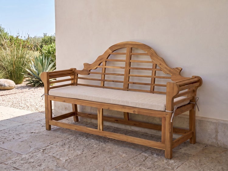 Gartenbank aus Holz mit geschwungener Rückenlehne und beiger Sitzauflage auf einer Terrasse vor einer Hauswand.