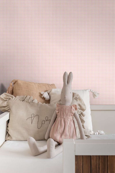 Vlies-Tapete mit kleinteiligem Karomuster für eine gemütliche Atmosphäre im Kinderzimmer vor einem Bett mit Stofftier und Dekokissen.