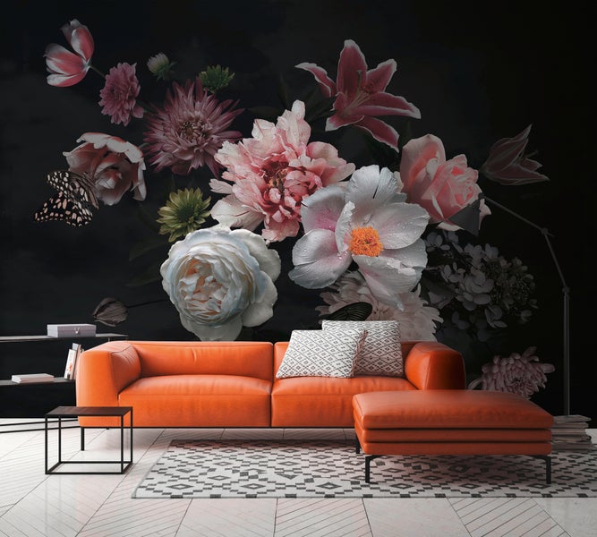 Modernes Wohnzimmer mit floraler Fototapete, die große Blumen auf dunklem Hintergrund hinter einem orangefarbenen Sofa zeigt.