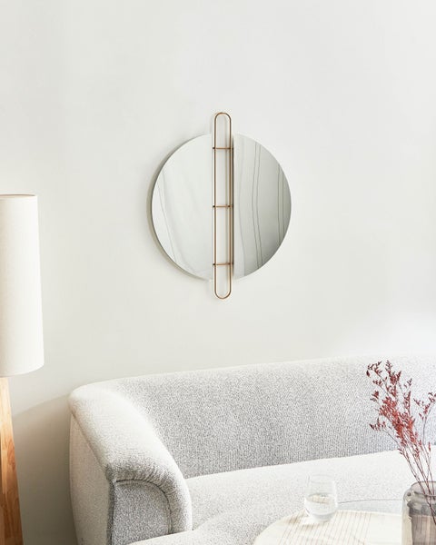 Runder Spiegel mit Metallrahmen über einem Sofa