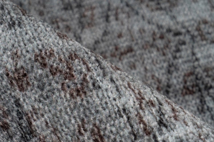 Nahaufnahme der Textur eines gewebten Teppichs mit grauem und braunem Muster.