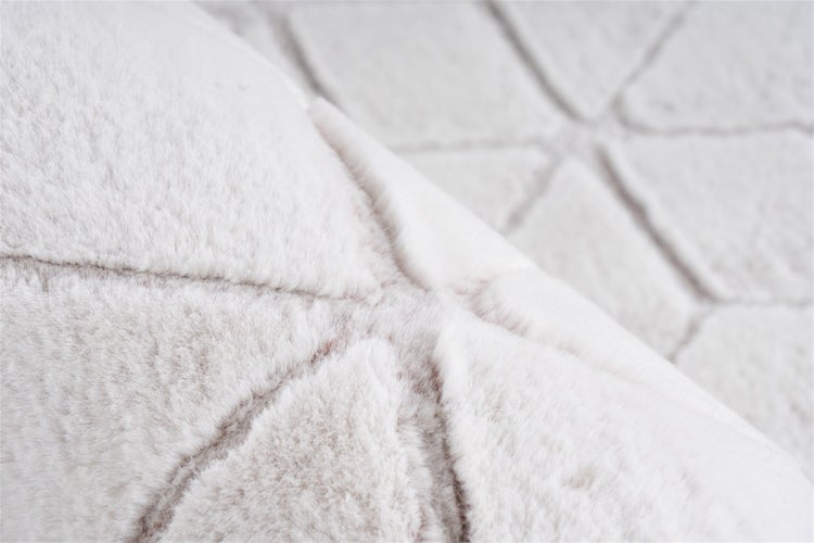 Nahaufnahme eines Teppichs mit weichem Flor und geometrischem Muster aus Dreiecken.