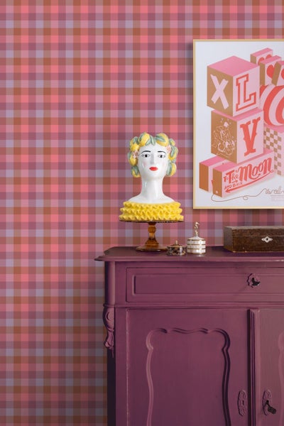 Vliestapete mit Karomuster in einem hellen Zimmer hinter einer Kommode mit dekorativer Büste und einem Wandbild.