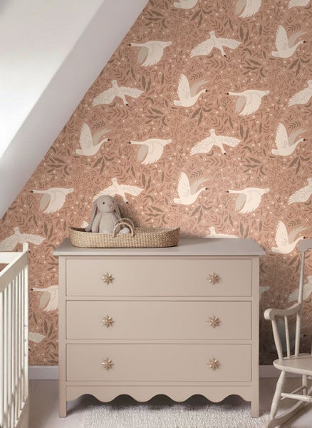 Szene mit einer Kommode vor einer mit einem Schwanenmotiv bedruckten Tapete in einem Zimmer.