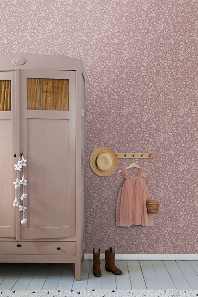 Vliestapete mit floralem Muster in einem Zimmer mit Holzschrank, Strohhut und Kleid an einer Hakenleiste.