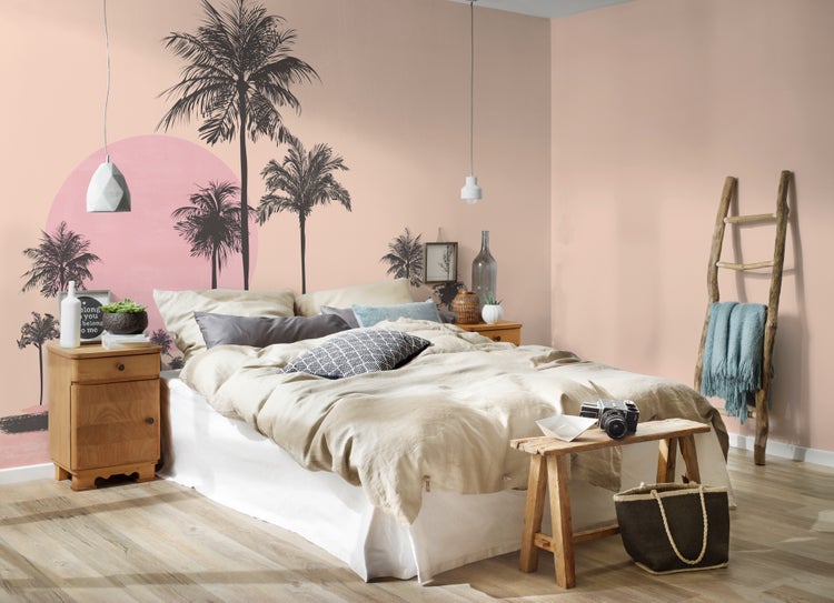 Schlafzimmer mit Fototapete mit Palmenmotiv, Bett, Nachttisch aus Holz und dekorativer Holzleiter.