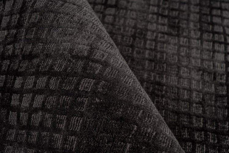 Detailansicht eines anthrazitfarbenen Teppichs mit Karomuster und strukturierter Oberfläche.